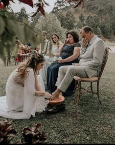 a group of people sitting on top of a grass covered field next to each other