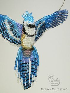 a beaded bird ornament with blue and white beads on it's wings