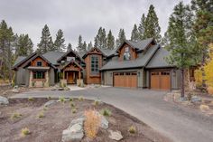 a large house with two garages and lots of trees in front of the house