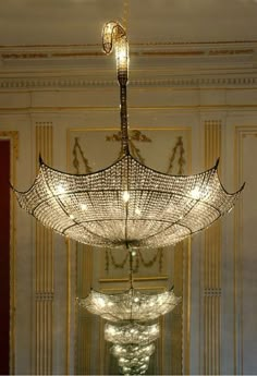 a chandelier hanging from the ceiling in a room with white walls and gold trimming