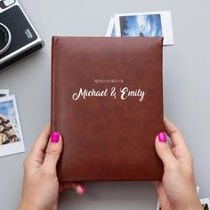 two hands holding a brown leather album with the words michael and enliy on it