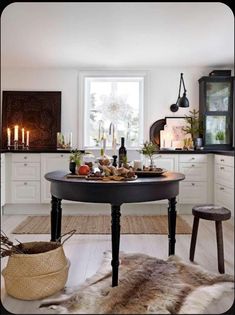 a dining room table with candles on it and an animal skin rug in the foreground