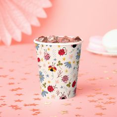 a paper cup filled with chocolate on top of a pink tablecloth next to stars