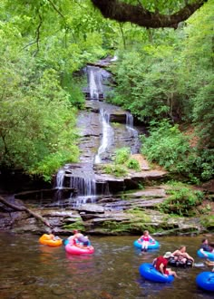 several people are tubling down a small waterfall