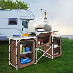 a camper trailer is set up with an outside kitchen and cooking area on the grass