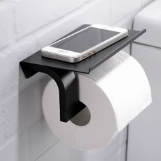 a cell phone is sitting on top of a toilet paper holder that holds a roll of toilet paper