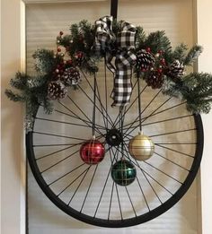 a bicycle wheel decorated with pine cones, ornaments and ribbon hanging on the front door