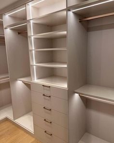 an empty walk in closet with white shelves and drawers