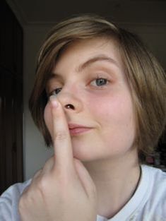 a young woman is holding her nose to her left side as she looks at the camera