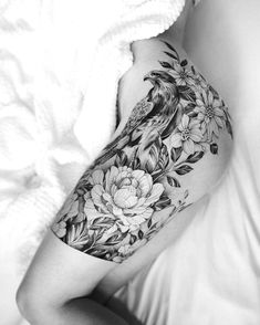 black and white photo of a woman's arm with flowers, birds and leaves on it