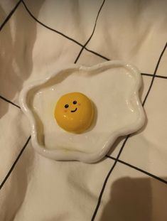 an egg shell with a smiley face painted on it sitting on a white tablecloth