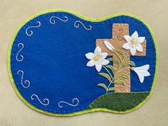 a blue and green mat with white flowers on it that has a cross in the middle