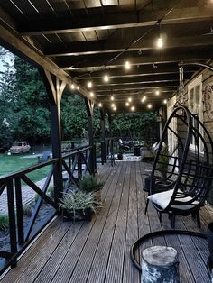 a porch with hanging chairs and lights on the ceiling is lit up by string lights