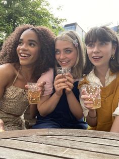 three women sitting at a table with drinks