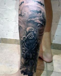 a man's leg with a black and grey tattoo design on it, featuring an image of a diving helmet