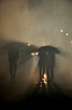 two people walking in the rain with umbrellas over their heads and one person holding an umbrella