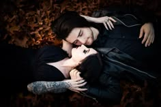 two people laying on the ground with their faces close to each other and one person has his eyes closed