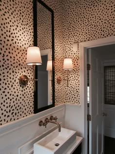 a white sink sitting under a bathroom mirror next to a wall mounted faucet