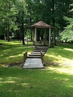 a gazebo sitting in the middle of a lush green park with stairs leading up to it