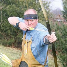 a man with blindfolded head holding a bow and arrow