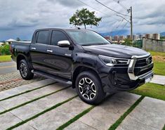 a black truck is parked on the side of the road in front of some grass