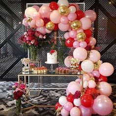 a table topped with lots of pink and red balloons