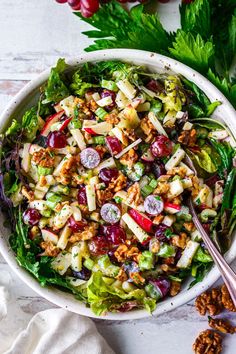 a white bowl filled with salad and topped with cranberries, apples, walnuts