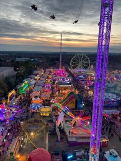 an aerial view of the fairground at dusk with ferris wheel and carnival rides in the foreground