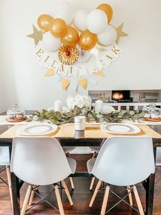 a dining room table set with white and gold balloons