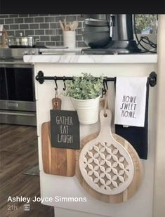 kitchen utensils hanging on the wall next to a potted plant and cutting board