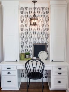 a white desk and chair in front of a wallpapered wall with a clock on it