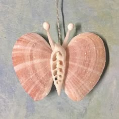 a pink and white butterfly ornament hanging from a chain on a gray surface