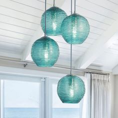 three blue lanterns hanging from the ceiling in a living room next to a large window