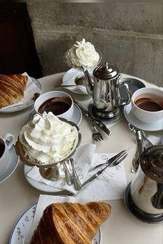 a table topped with croissants and cups of coffee