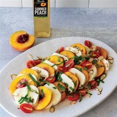 a white plate topped with sliced peaches next to a bottle of sunflower seed oil