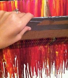 a person is holding a piece of art with red and yellow paint dripping on it