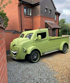 a green pick up truck parked in front of a brick building with windows on the side