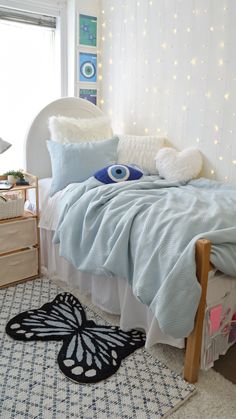 a bedroom with white walls and blue bedding has a butterfly rug on the floor