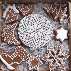 a box filled with lots of decorated gingerbread cookies on top of white frosting