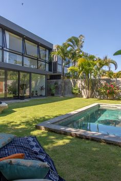 an outdoor swimming pool with lounge chairs and umbrellas in the foreground, surrounded by palm trees