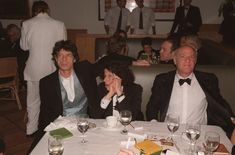 three people sitting at a table with wine glasses