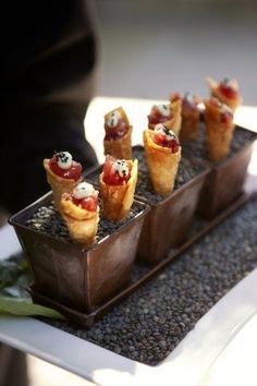 small desserts are arranged in trays on top of some gravel and green leaves