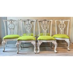 four silver chairs with green cushions in a room