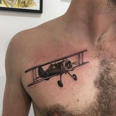 a man's chest with a small airplane tattoo on his left side ribcage