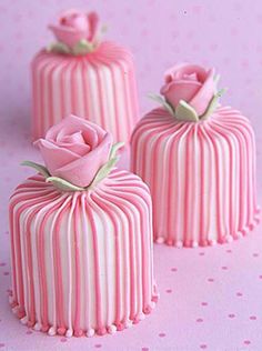 three pink striped cakes sitting on top of a table next to each other with roses