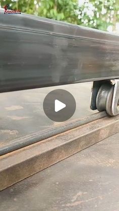 a close up of a skateboard on a metal rail with trees in the background