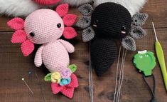 three crocheted stuffed animals sitting next to each other on a wooden table with knitting needles