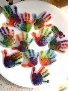 a white plate topped with lots of colorful hand prints