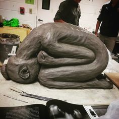 a man is working on a sculpture in the shape of a snake with his eyes closed