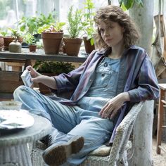 a woman sitting in a chair with potted plants behind her